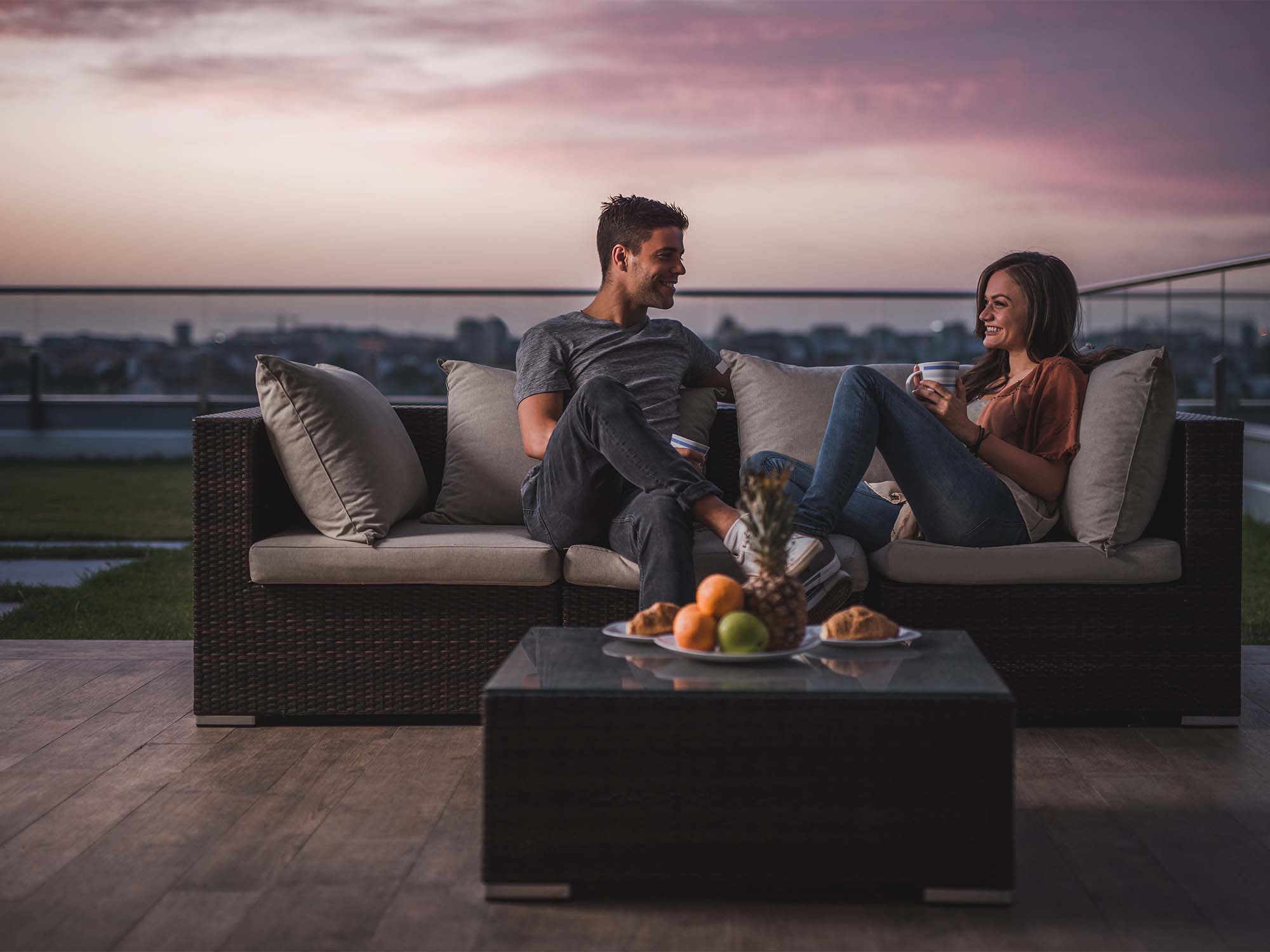 image of a couple enjoying food and sunset on an open deck of a high rise building 