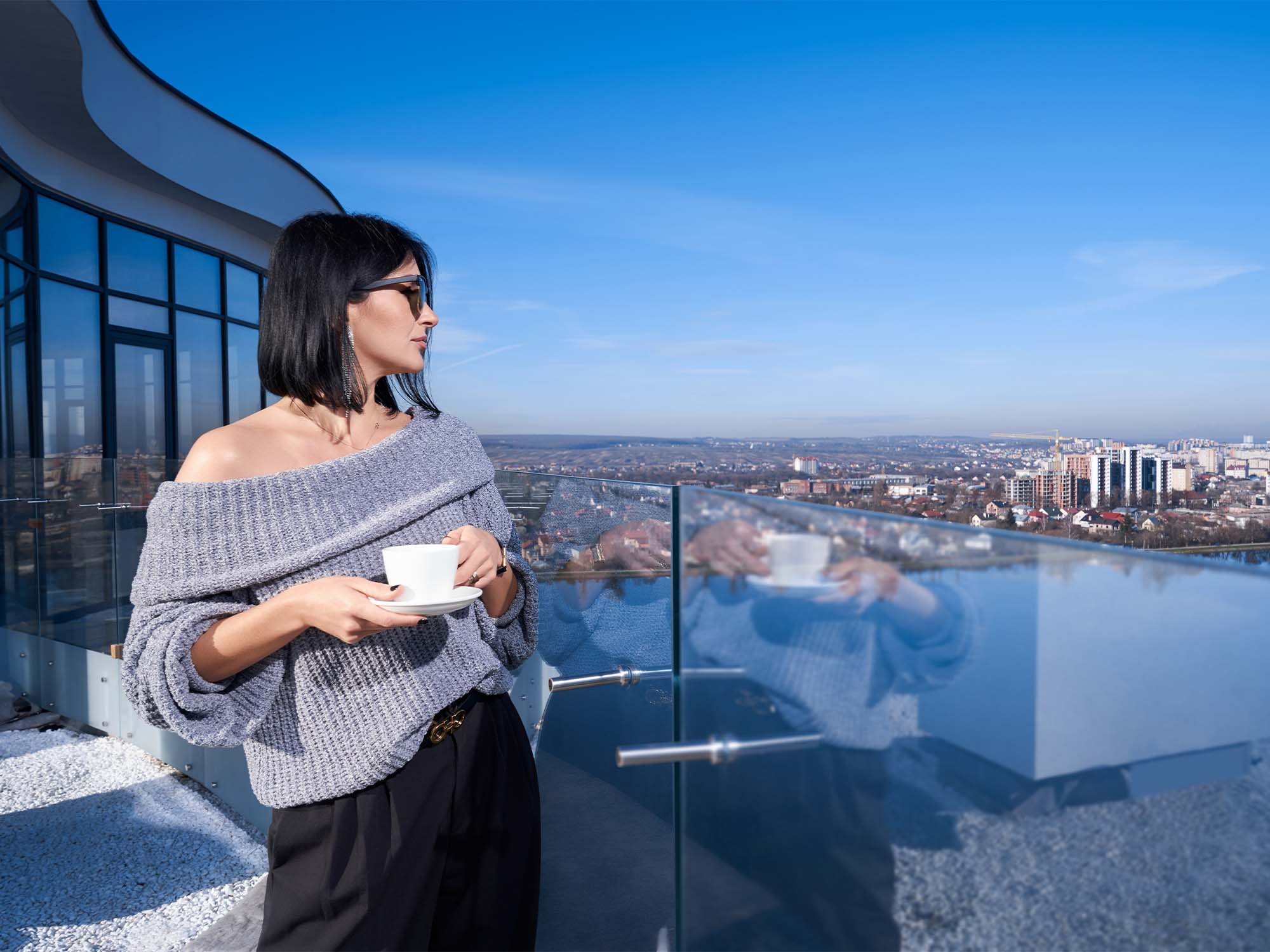 image of a woman enjoying coffee and cityscape view from a highrise building terrace